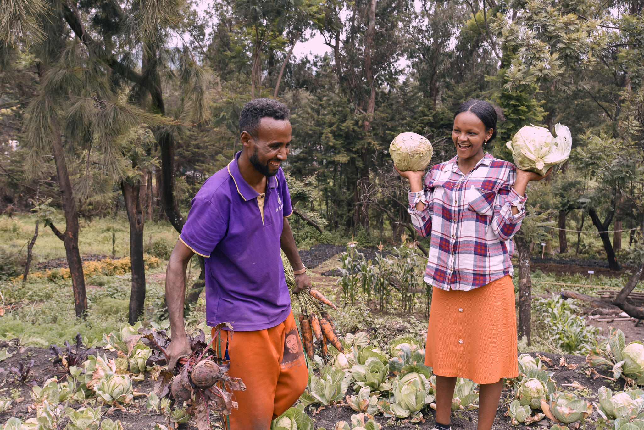 Shume and her husband, Misgana in the land with some of the vegetables they harvested after UN Women’s support.
