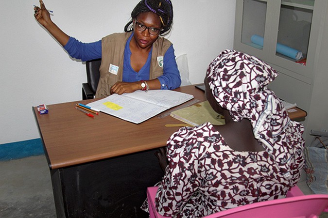 Carine Nguetsop, travailleuse sociale de terrain, avec des partenaires de mise en œuvre d'ONU Femmes,  conseillant un ancien otage de Boko Haram dans l'une des salles de sécurité de la WCS au camp de réfugiés de Minawao.