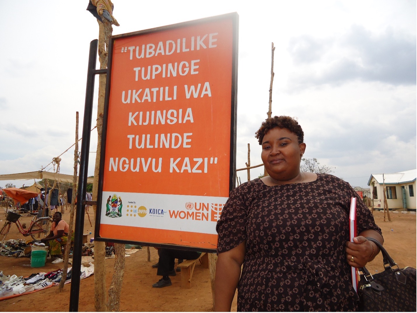 Veronica Charles Mfuko is standing in front of the UN Women banner at Segese market in Msalala district, where she and her colleagues organized GBV sensitization session to the market vendors. Photo: UN Women / Sohee Kim