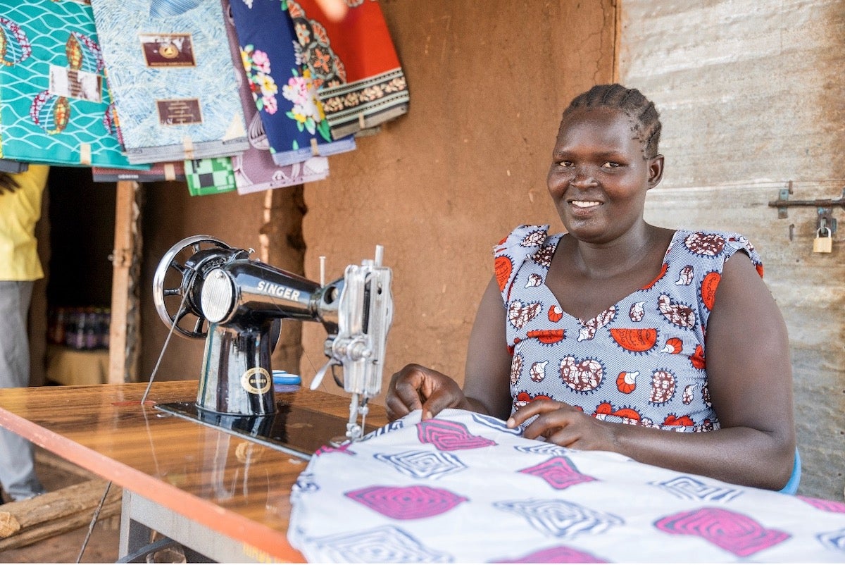 Alice Ledu in Bidi Bidi Settlement attending to the tailoring enterprise that she started using proceeds from the catering business skills.  Photo credit: UN Women / Jeroen van Loon