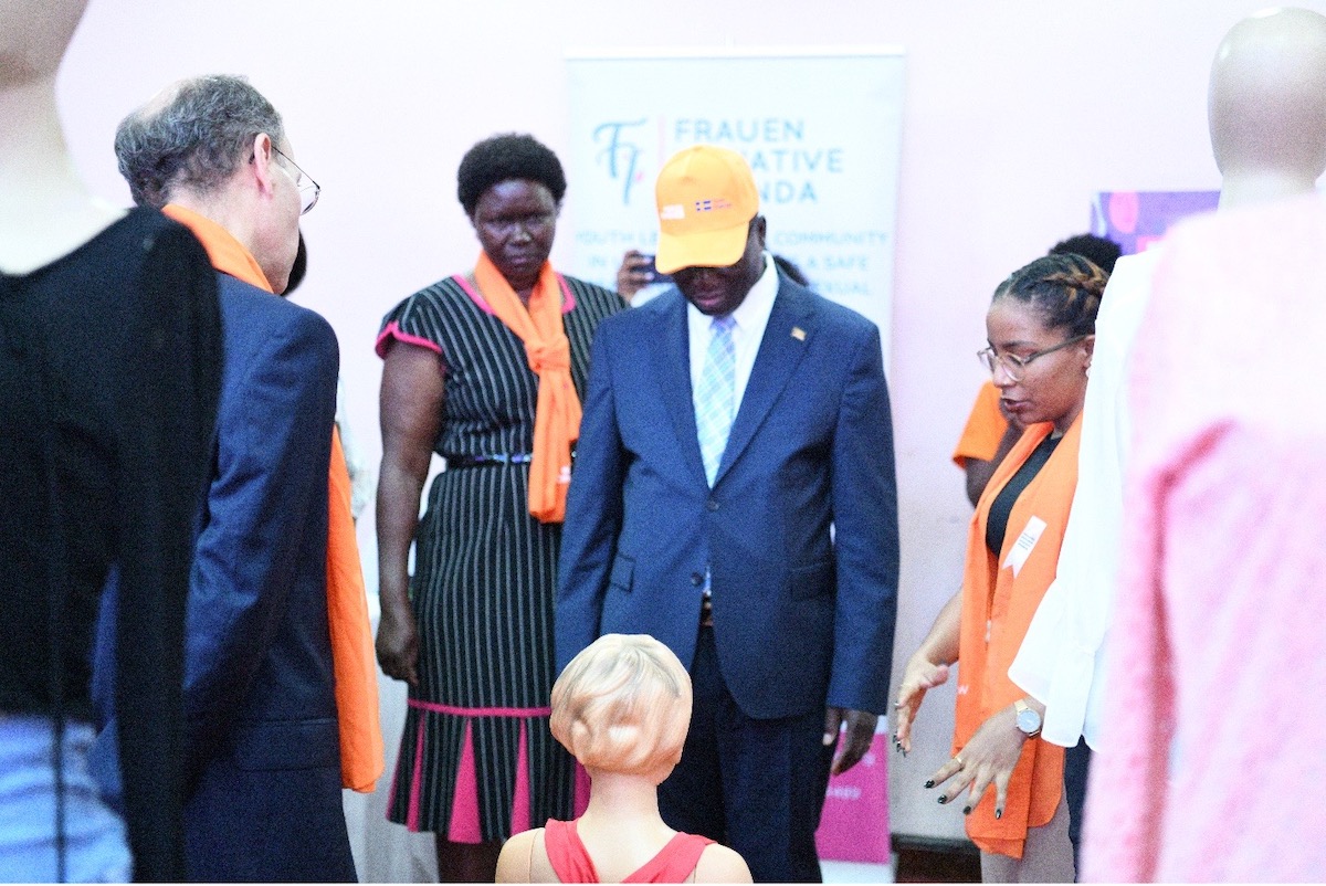 Safina Virani (right) takes Permanent Secretary Ministry of Gender Aggrey Kibende (center) through the exhibition, explaining the child mannequin. Guests of Honour at National Launch included EU Delegation (UN Women/Eva Sibanda)