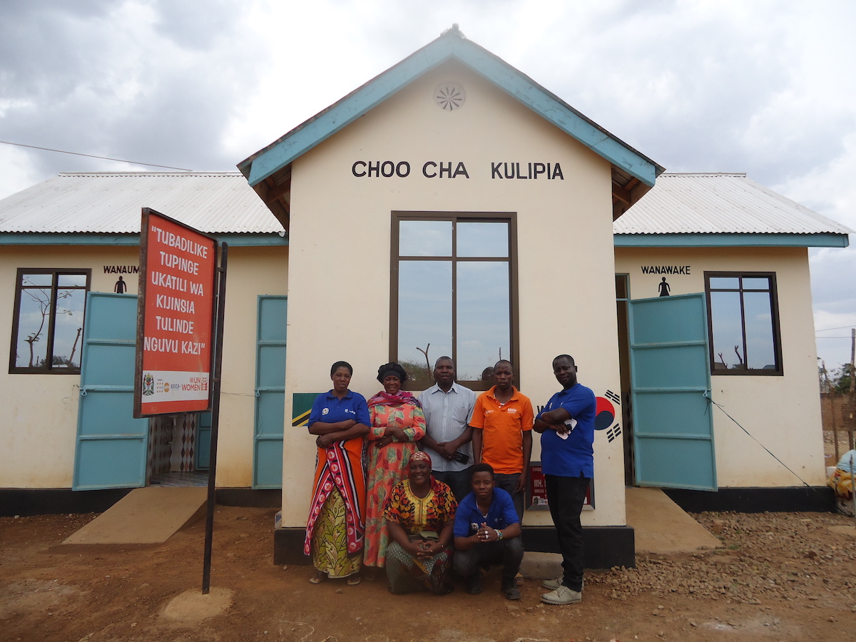 Mwanamwiga Mihayo, second from the left, poses with market committee members in front of the public toilets and hand wash facilities constructed with support from UN Women and KOICA at the Segese market in Shinyanga. Photo: UN Women/Sohee Kim 