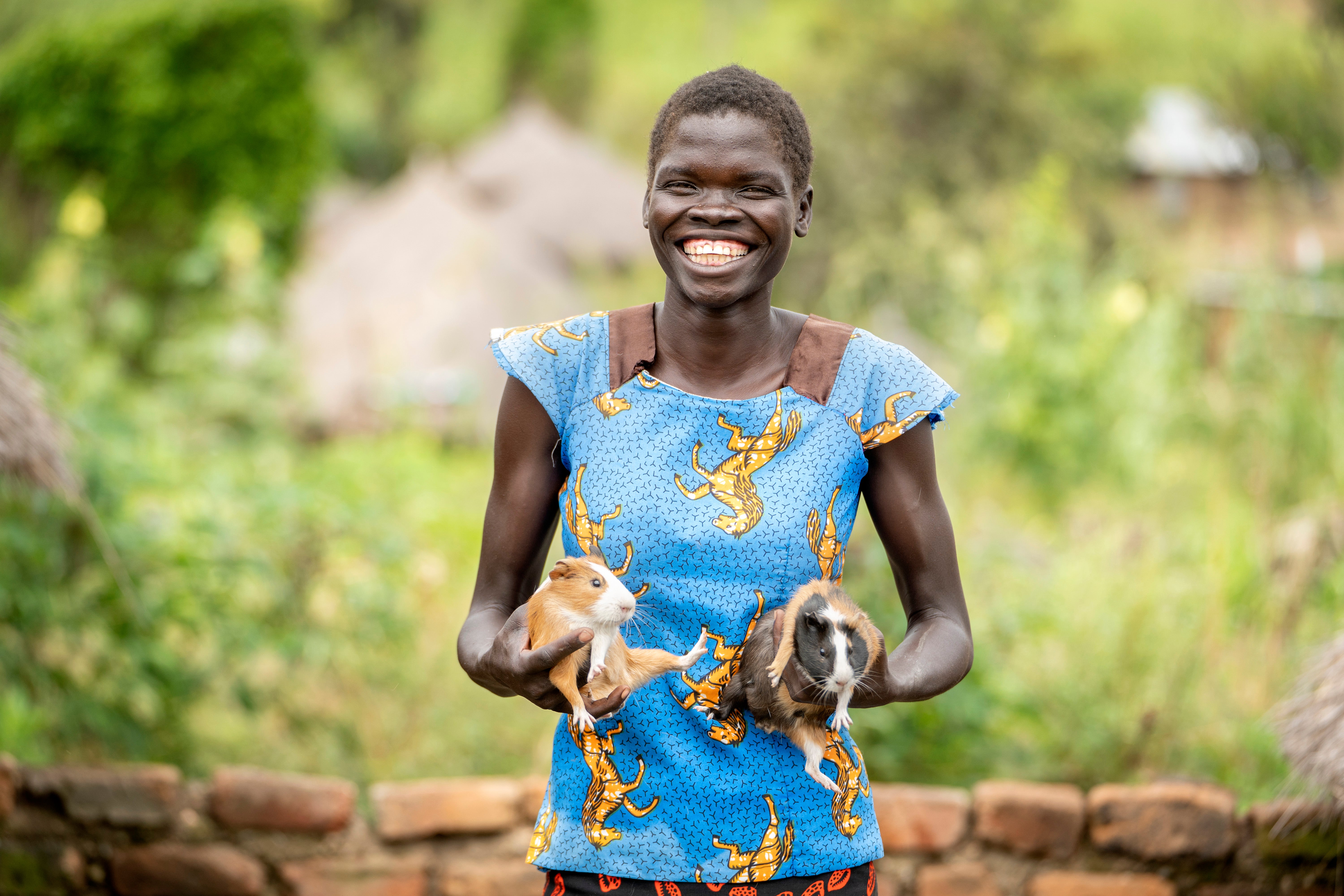 Mary showing some of the small animals that she raises in her compound. Photo Credit: UN Women/Jeroen Van Loon
