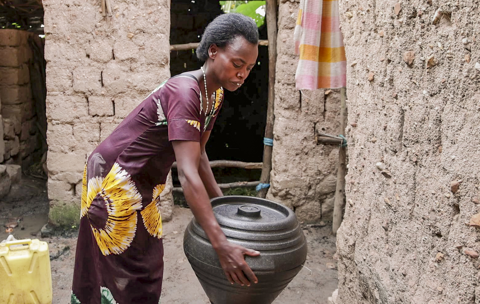Woman holding a cooking pot, and participating in household chores.