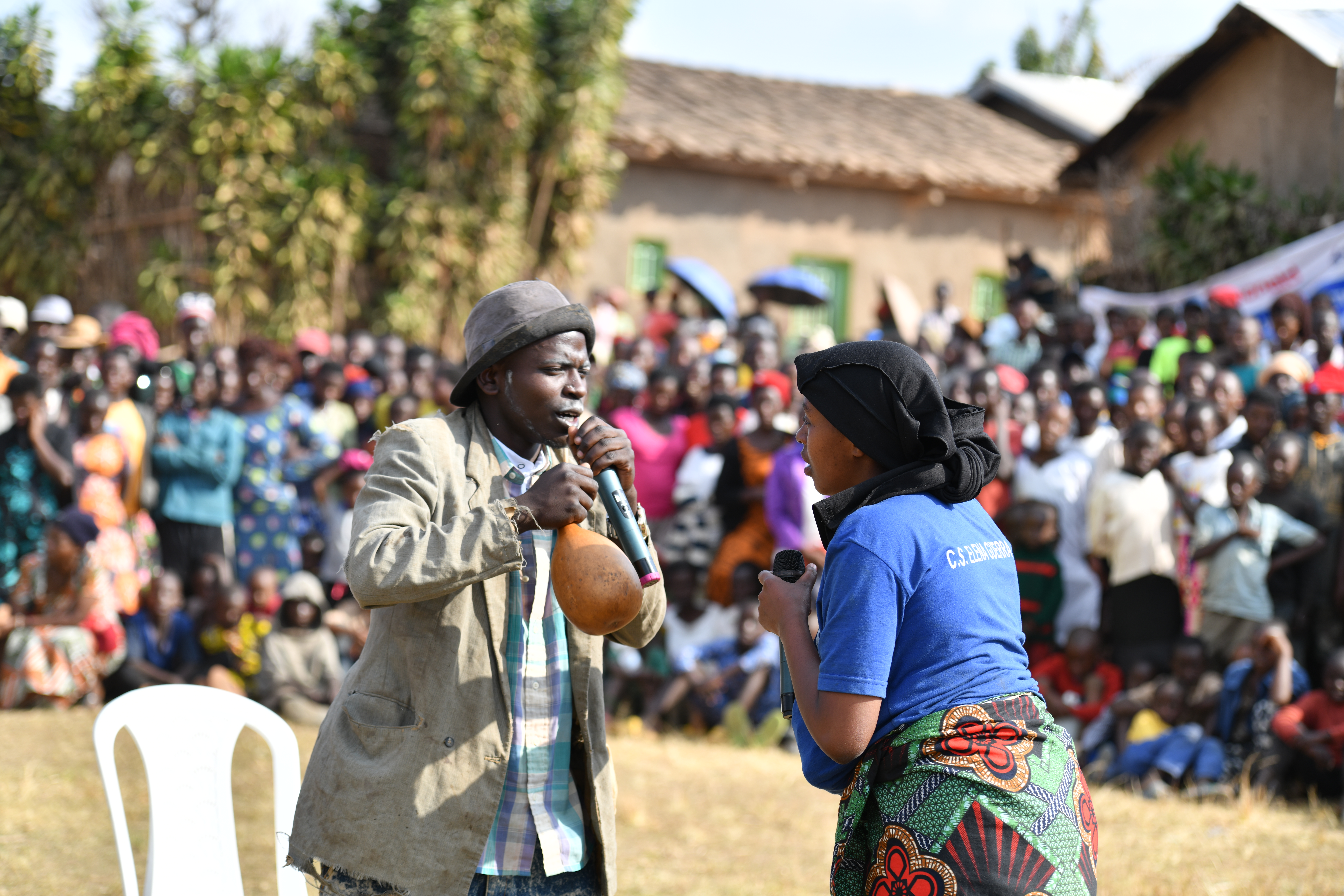 Two actors performing during the public awareness raising event on unpaid care work in Nyaruguru district