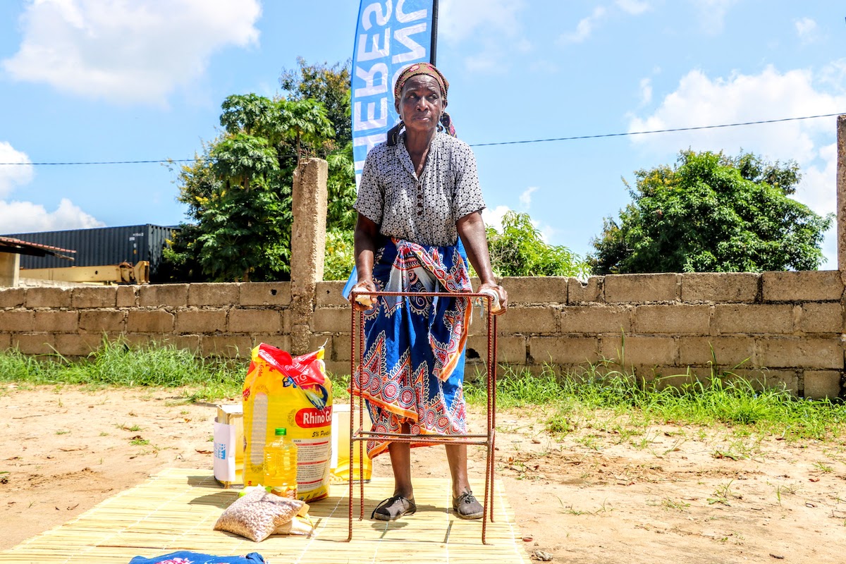 An elderly woman with a disability poses next to her humanitarian kit items, Boane -Maputo. Photo: UN Women