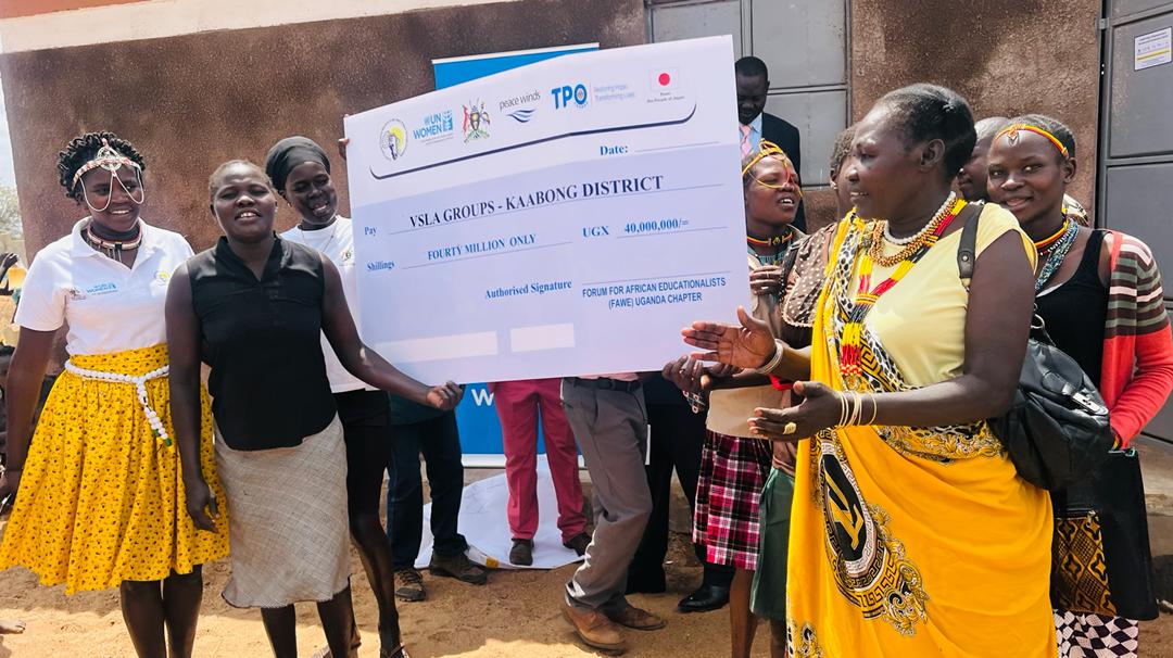 Representatives of savings groups in Kabong established under the LEAP project displaying a dummy check of funds received to boost the groups saving and lending portfolio