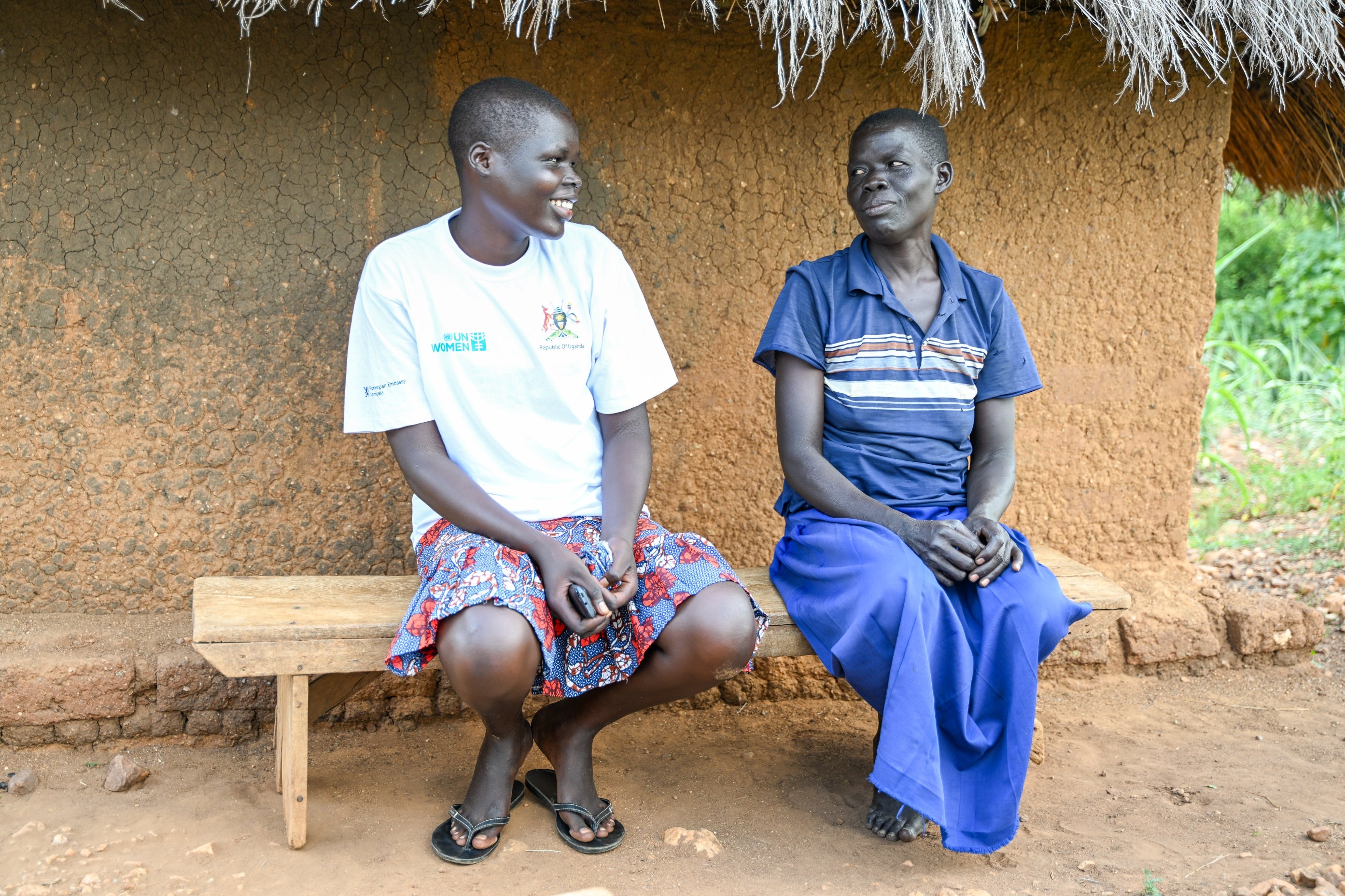 Annet Luka, a South Sudanese refugee, shares a light moment with her mother outside their home in Terego, northern Uganda. Annet has already helped her family by making the wooden bench that she is sitting on. (Photo: UN Women/James Ochweri)