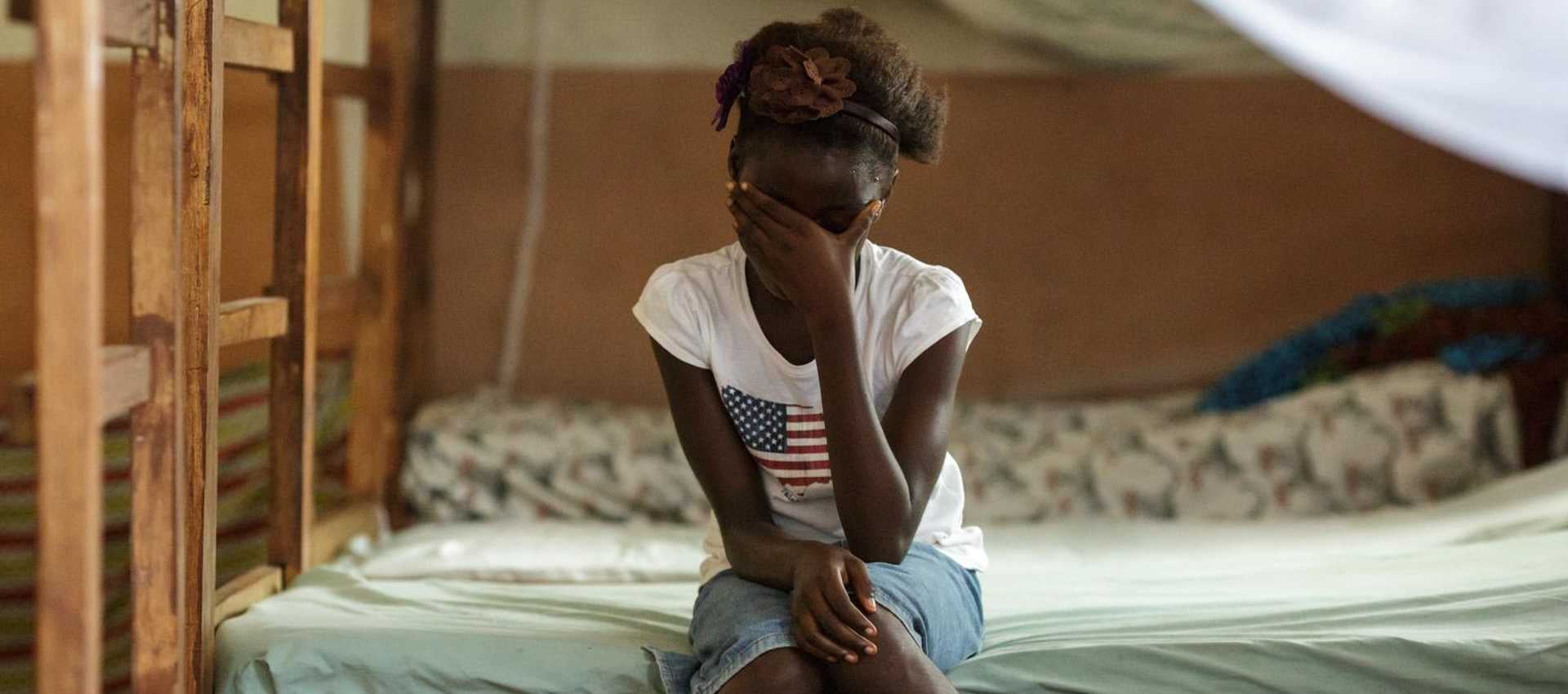 Rebecca (name changed), 10, sits on her bed in the dorm of the safe house of UNICEF partner NGO Amazonian Initiative Movement in the town of Masethleh, Port Loko District, Sierra Leone. She ran away from her home where her familiy was planning on training her as a female genital mutilation practioner. Photo: UNICEF/UNI150843/Asselin.