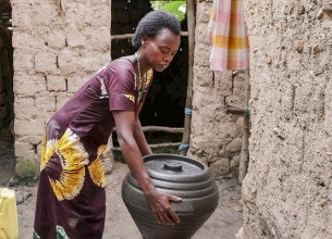 Woman holding a cooking pot, and participating in household chores.